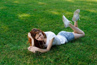 Kadın bahçedeki çimlerde uzanıyor. Açık hava eğlencesi.