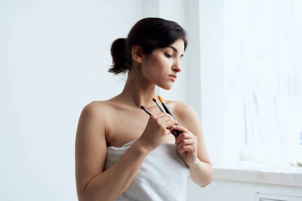 Vacker kvinna i handduk badrum makeup borste hudvård — Stockfoto