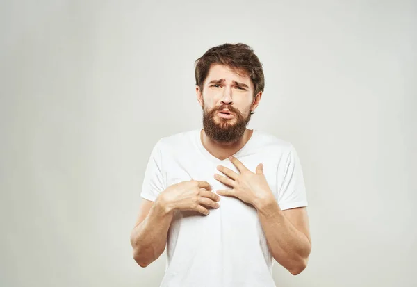Ένας άντρας με ένα λευκό μπλουζάκι σε ένα ελαφρύ φόντο συναισθήματα μοντέλο χειρονομίες με τα χέρια Αντιγραφή χώρου — Φωτογραφία Αρχείου