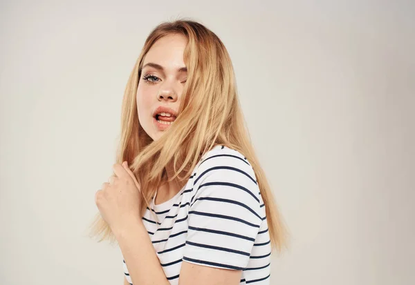 Блондинка в полосатой футболке на бежевом фоне обрезанный вид — стоковое фото