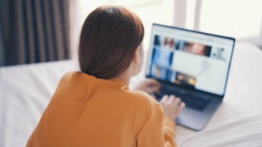 Evde internet iletişiminde dizüstü bilgisayarın önünde yatan kadın.