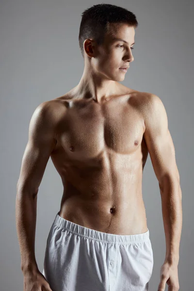 Портрет молодого спортсмена с накачанным туловищем на сером фоне — стоковое фото