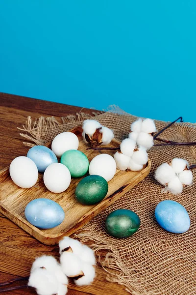 Huevos de Pascua sobre tabla de madera decoración vacaciones tradición fondo azul —  Fotos de Stock