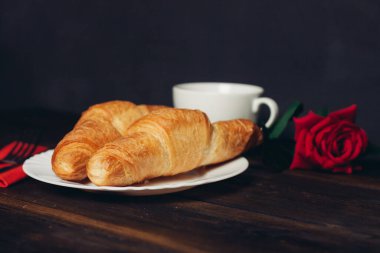 Tabakta çıtır kruvasan ve ahşap kahve fincanı.