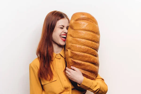 Grande pão de pão na mão de uma mulher em uma camisa amarela em um fundo leve — Fotografia de Stock