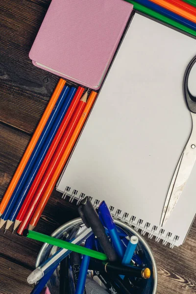 Notepads colored pencils and stationery in a glass on a wooden table top view — Stock Photo, Image