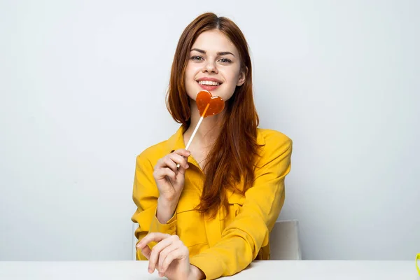 Cheerful pretty woman holding heart-shaped lollipop owner — Stock Photo, Image