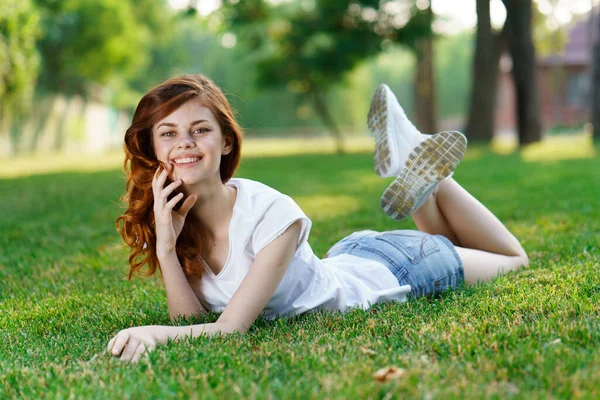 Niedliche rothaarige Frau liegt auf dem Rasen im Park — Stockfoto
