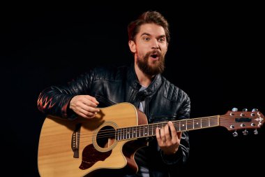 Elinde gitar olan bir adam deri ceketli müzik performansı rock yıldızı modern tarz koyu arkaplan
