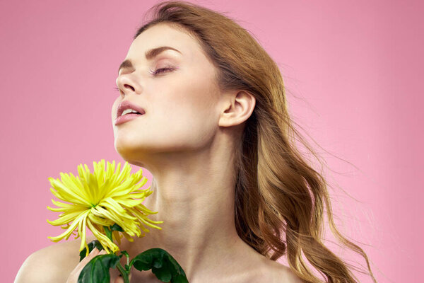Portrait of a woman with yellow flowers on a pink background Makeup on the face