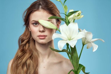 Mavi arka planda beyaz çiçeklerle dolu bir buketi olan çıplak omuzları olan güzel bir kadın.