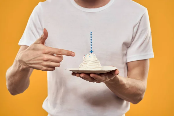 黄色の背景の誕生日デザートに手に誕生日ケーキを持つ男 — ストック写真