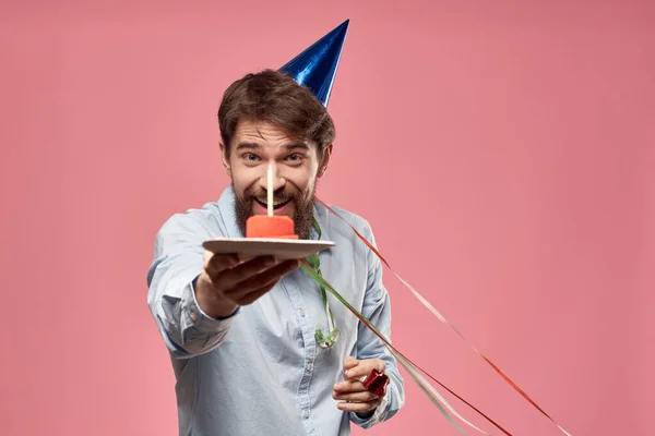 Homme barbu avec langue de gâteau sur un fond rose vue recadrée et une casquette bleue sur sa tête — Photo