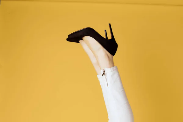 Kvinnor inverterade svarta skor mode gul bakgrund — Stockfoto