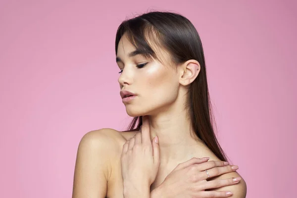 Brunette bare skuldre klar hud kropspleje lyserød baggrund - Stock-foto