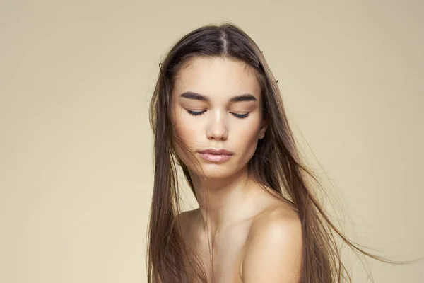 Bella donna spalle nude capelli lunghi cura del corpo sfondo beige — Foto Stock