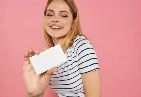 Woman with white card on pink background gesturing with hands cropped view