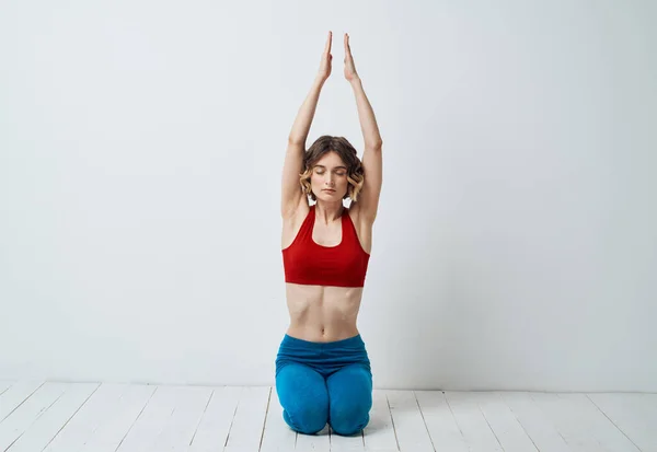 Seorang wanita duduk di lantai ringan di dalam ruangan dengan tangannya bergabung dengan asanas yoga untuk bersantai — Stok Foto
