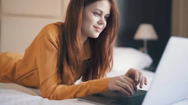 Emotionele vrouw in de slaapkamer liggend op de bank met een laptop communiceren — Stockfoto