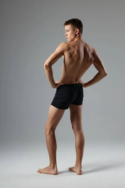Спортивный человек с накачанным телом черные шорты задний вид изолированный фон — стоковое фото