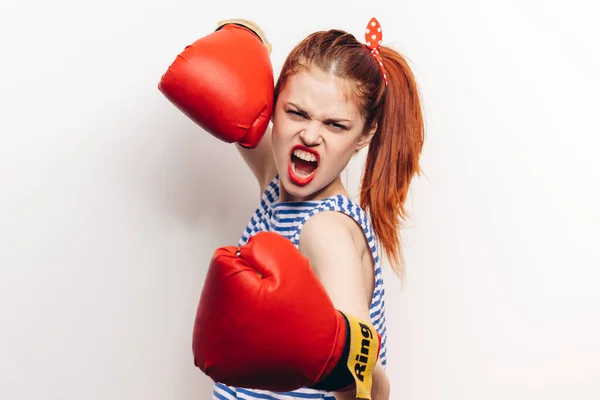 Mujer en una camiseta a rayas y en guantes rojos se dedican a la agresión de boxeo maquillaje boca abierta — Foto de Stock