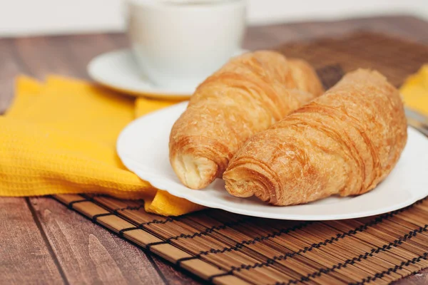 Krispiga färska croissanter på en tallrik på bordet frukost dessert — Stockfoto