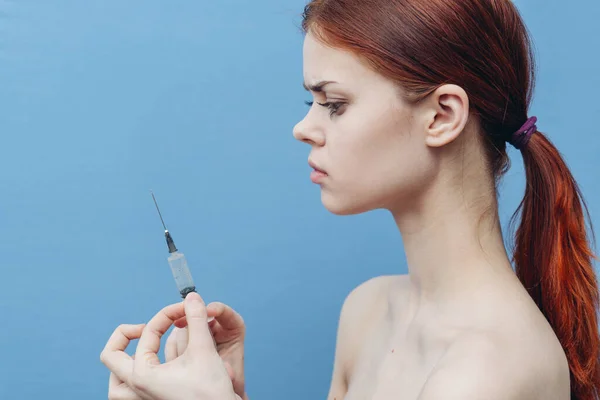 Mujer con jeringa en las manos sobre fondo azul inyección rejuvenecimiento botox vista lateral —  Fotos de Stock