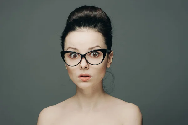 Pretty woman naked shoulders gathered hair glasses emotions — Stock Photo, Image