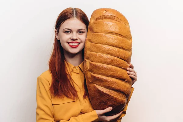 Hermosa mujer en una camisa amarilla sostiene un pan grande en su mano —  Fotos de Stock