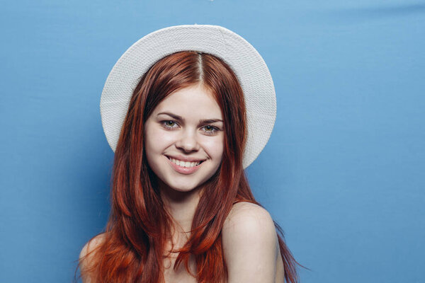 cheerful red-haired woman in hat naked shoulders glamor blue background