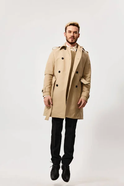 Hombre rubio guapo en un abrigo beige y pantalones sobre un fondo claro — Foto de Stock