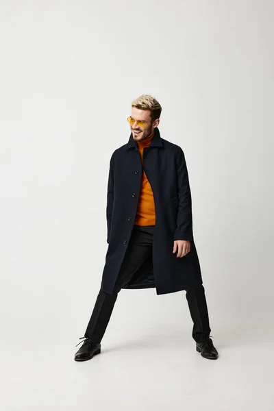 Hombre rubio en ropa de moda abrió sus piernas y pantalones de suéter naranja de fondo claro — Foto de Stock