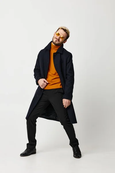 Hombre en un abrigo oscuro suéter naranja pantalones modelo emociones Copiar Espacio — Foto de Stock