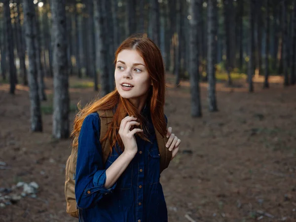 Mulher sem camisa de cabelos vermelhos com uma mochila nas costas descansando em uma floresta de pinheiros e vista cortada — Fotografia de Stock