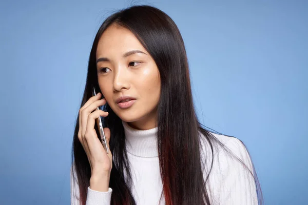 파란 배경으로 핸드폰으로 통화하는 아시아 여성 — 스톡 사진