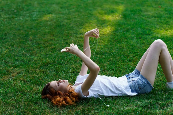 Csinos nő fekszik a gyepen a parkban szabadidő — Stock Fotó