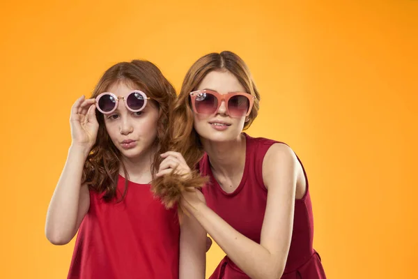 Две сестры и веселые солнцезащитные очки мода Дружба желтый фон семьи — стоковое фото