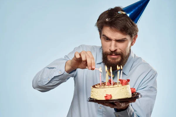 Un hombre con una camisa con un pastel en las manos y una gorra festiva en la cabeza —  Fotos de Stock