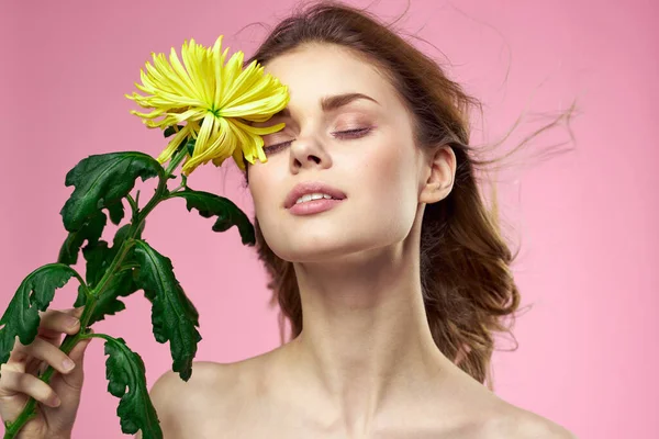 Красивая девушка с желтым цветком на розовом фоне обнаженные плечи макияж — стоковое фото