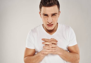 Beyaz tişörtlü adam üzgün duygular model ışık arka planı elleriyle hareket ediyor.