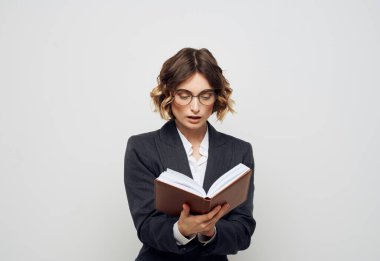 Klasik takım elbiseli, açık kitap gözlüklü, yüzü kırpık bir kadın.