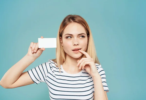 Una donna con una maglietta a righe tiene in mano un biglietto da visita su uno sfondo blu — Foto Stock