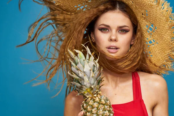 Mulher em um chapéu de palha com abacaxi em suas mãos cabelo ondulado frutas exóticas você verão azul fundo férias — Fotografia de Stock