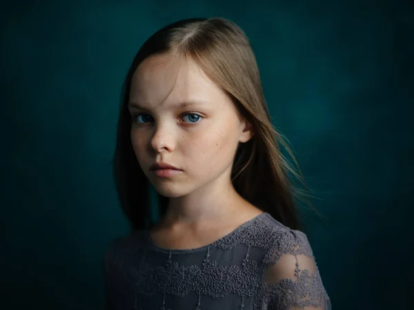 Retrato de uma menina de olhos azuis em um vestido cinza em um fundo verde close-up bela cara — Fotografia de Stock