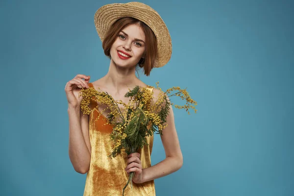 Mooie vrouw in hoed boeket bloemen vakantie blauwe achtergrond — Stockfoto