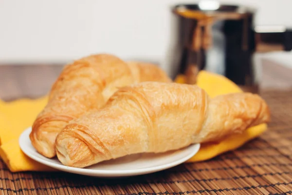 Croissanter i en tallrik på bordet måltid dessert till frukost en kopp kaffe — Stockfoto