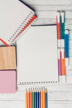 Not defteri renkli kalemler tahta masa üzerindeki çıkartmalar.