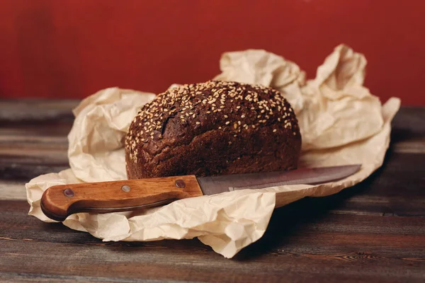 rye bread baking on paper packaging wooden table and sharp knife