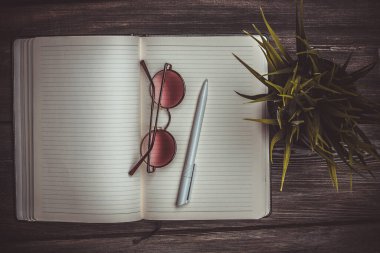 Not defteri bardakları ve saksıda bir çiçek Tahta bir masanın üstünde kalem ofisi