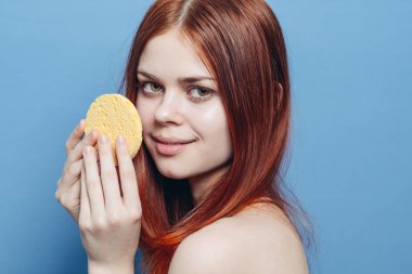 Yüzünün yanında çıplak omuzları olan kızıl saçlı hoş bir kadın.